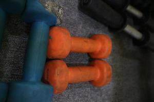imagem editorial de alguns halteres laranja azuis no tapete para se exercitar na academia foto