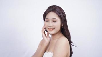 menina asiática compõe um sorriso fofo mão a orelha isolado no fundo branco