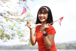 mulher asiática animada segurando a bandeira da Indonésia no dia da independência da Indonésia foto