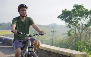 jovem asiático andar de bicicleta pela manhã foto