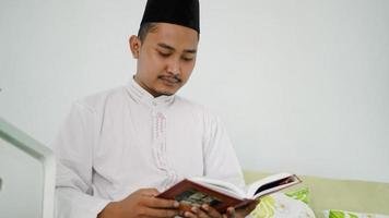 retrato de homem muçulmano asiático lendo o Alcorão Sagrado em casa foto
