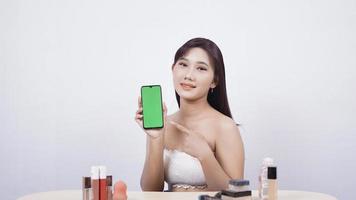 bela maquiagem asiática mostrando o gesto ok da tela do smartphone isolado no fundo branco foto
