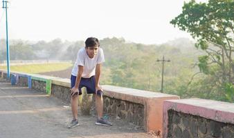 jovem asiático tendo streaching antes de correr pela manhã foto