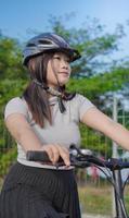 jovem mulher asiática gostando de andar de bicicleta quando parou na manhã de verão foto