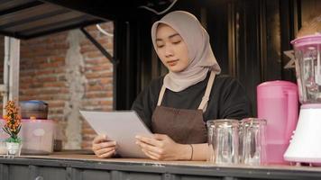 bela garçonete asiática lendo a lista de menu seriamente no contêiner de cabine de café foto