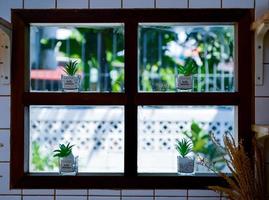 a janela da cozinha é decorada com vasos de flores. a luz natural externa ilumina a cozinha. foto