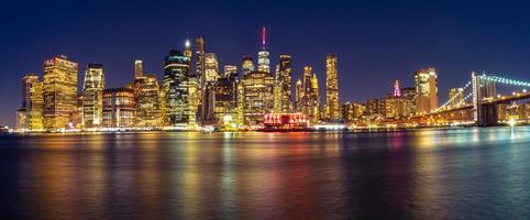 o horizonte de manhattan durante a visão noturna com a ponte do brooklyn foto