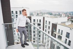 sorrindo jovem arquiteto ou construtor de engenharia no capacete com tablet sobre grupo de construtores no canteiro de obras, arquiteto assistindo a uma construção, negócios, construção, indústria, conceito de pessoas foto