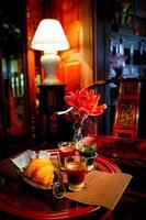 mesa de jantar com croissant e vidro em fotografia com pouca luz. cartão postal vintage retrô. gótico, europa, estilo de interior vintage histórico. ninguém. foto