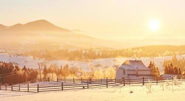 a misteriosa paisagem de inverno é majestosa montanhas no inverno. pôr do sol fantástico. gravando casas na neve. cartão postal de cortesia da foto. Cárpatos foto