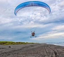 parapente voando sobre a praia do oceano pacífico em kanchatka foto