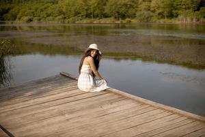 jovem relaxante no cais de madeira no lago calmo foto