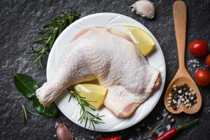 Coxa de frango crua no prato branco para cozinhar comida asiática tailandesa alecrim frango com limão na mesa de comida de madeira foto