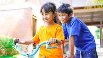 duas crianças brincando de bicicleta no jardim atrás da casa foto