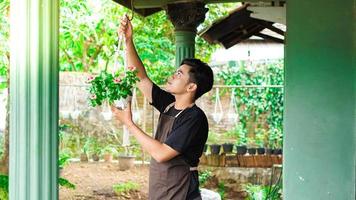 homem asiático pendurando plantas em casa faz uma bela decoração foto