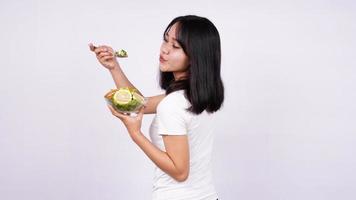 jovem mulher asiática feliz comendo salada saudável com fundo branco isolado foto