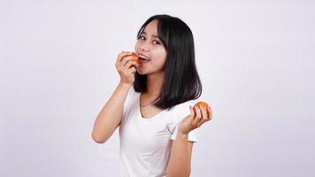 fechar belas mulheres asiáticas com um tomate isolado no fundo branco foto