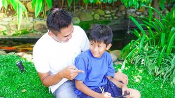 pai e filho jogam jogos móveis no parque foto