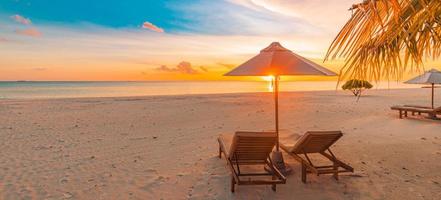 praia deslumbrante. cadeiras guarda-chuva sob folhas de palmeira. férias de verão na praia, destino de turismo de férias de casal. paisagem tropical romântica. praia panorâmica tranquila, banner de paisagem tropical foto