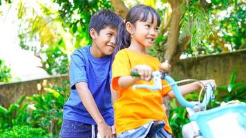 duas crianças brincando de bicicleta no jardim atrás da casa foto