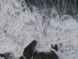 vista aérea de cima para baixo de ondas gigantes do oceano batendo e espumando na praia de coral foto