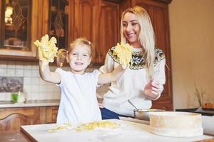 feliz sorridente mãe na cozinha assa biscoitos com a filha. foto