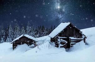 noite com estrelas. paisagem de natal. casa de madeira na aldeia de montanha. paisagem noturna no inverno foto