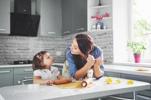 mãe amando o forno para a filha do biscoito. foto