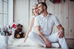 casal jovem feliz no natal, belos presentes e árvore ao fundo foto