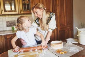 menina feliz com sua mãe cozinhar biscoitos. foto