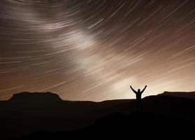 silhueta de uma aventura de fotógrafo feliz trekking na montanha com estrelas em movimento de fantasia real no céu noturno. conceitual de natureza incrível com grande viagem de sonho e cena de viagem foto