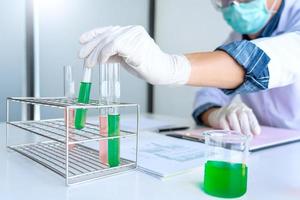 cientistas pesquisando em laboratório em jaleco branco, analisando luvas, olhando para amostra de tubos de ensaio, conceito de biotecnologia foto