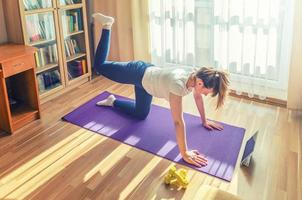 jovem mulher atraente em roupas esportivas fazendo exercícios em casa foto