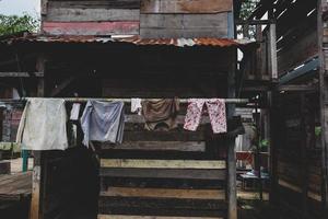 roupas penduradas para secar na frente de uma velha cabana de madeira em uma favela foto