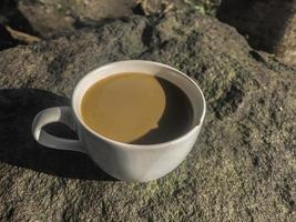 xícara branca de café cremoso isolado no fundo de pedra foto