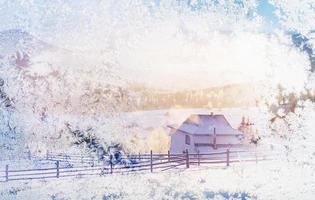 olhar através de uma janela congelada. montanhas incríveis à luz do sol da manhã. pequena aldeia acolhedora. Cárpatos, Ucrânia, Europa. mundo da beleza. feliz Ano Novo foto
