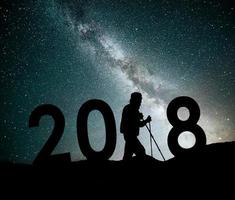 silhueta jovem alpinista para o fundo de ano novo de 2018 da galáxia via láctea em um tom de céu escuro estrela brilhante foto