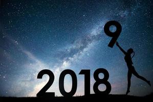 jovem silhueta. feliz ano novo de 2018. fundo da Via Láctea em um tom de céu escuro estrela brilhante. mudança de conceito ano 2017 para 2018 foto