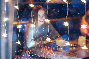 jovem e bela mulher sentada no café, tomando café. natal, feliz ano novo, dia dos namorados, conceito de férias de inverno foto