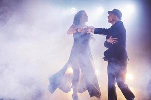 dançarinos habilidosos se apresentando no quarto escuro sob a luz e a fumaça do show. casal sensual realizando uma dança contemporânea artística e emocional foto