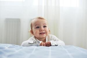 menina de um ano sentada no chão sorrindo em branco foto