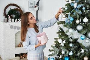 linda garota de pijama decorando a árvore de natal foto