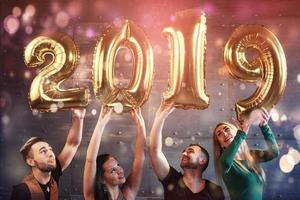 um grupo de jovens alegres segura números que indicam a chegada de um novo ano de 2019. a festa é dedicada à celebração do ano novo. conceitos sobre estilo de vida de união da juventude foto