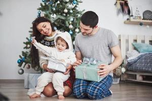 família feliz no Natal de manhã abrindo presentes juntos perto do abeto. o conceito de felicidade e bem-estar familiar foto