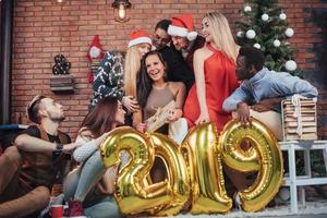 grupo de velhos amigos alegres se comunicam. novo ano de 2019 está chegando. comemore o ano novo em um ambiente acolhedor foto