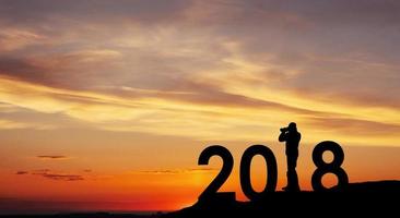 silhueta jovem fotógrafo para fundo de ano novo de 2018 do pôr do sol foto