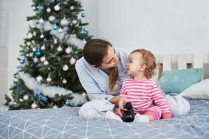 família feliz mãe e filha na manhã de natal na árvore de natal com presentes foto