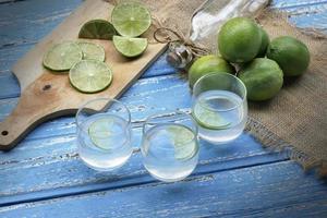 suco de limão e limão em uma mesa de madeira azul foto