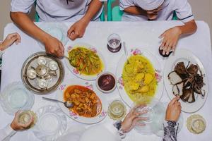 vista superior do ketupat lebaran, prato comemorativo tradicional indonésio de bolo de arroz com vários acompanhamentos servidos na mesa durante eid mubarak foto