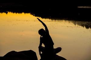 silhuetas de uma mulher fazendo ioga ao pôr do sol foto